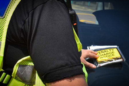 Enforcement officer placing ticket on windscreen