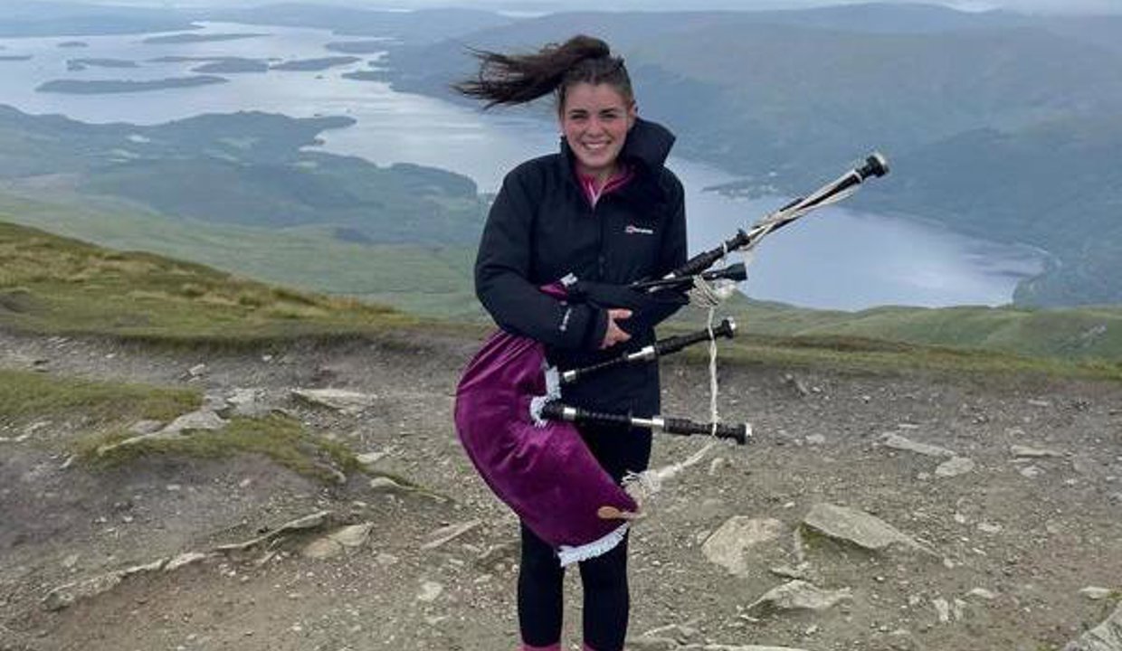 Megan holding her bagpipes at the top of Ben Lomond