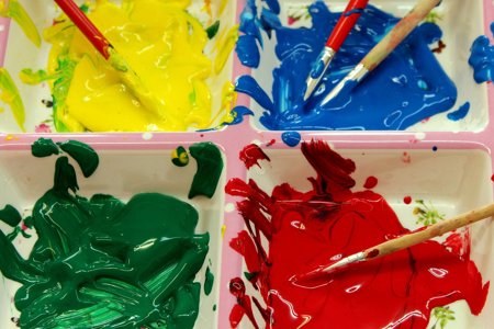 Yellow, blue, green and red paint with paint brushes