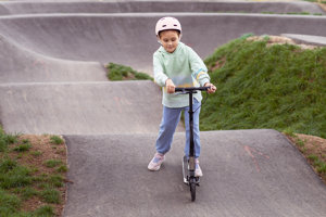 Child on a scooter going along the pump track