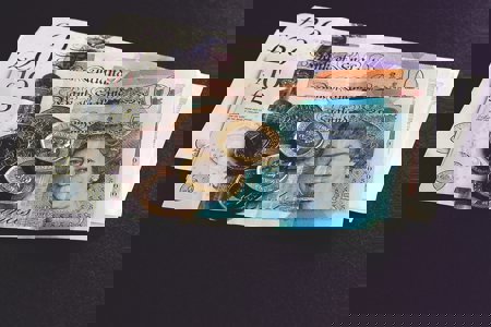 Pound coins sitting on top of bank notes 