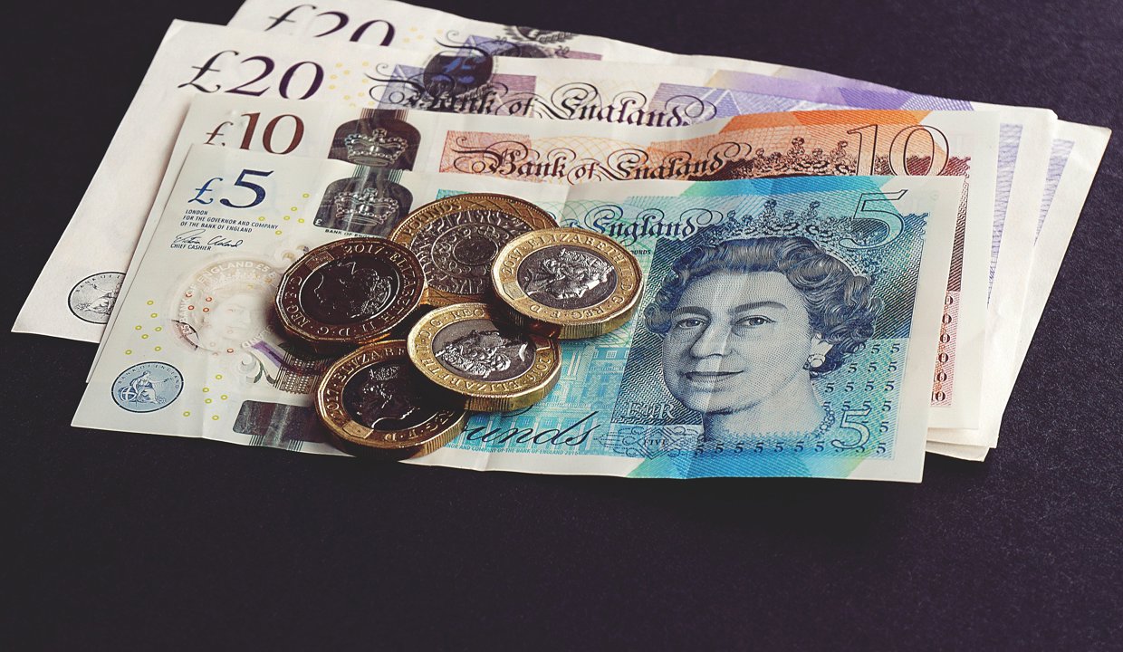 Pound coins sitting on top of bank notes