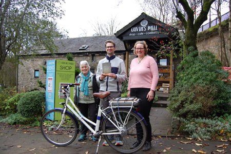 Three people stand outside the Gavin’s Mill premises in Milngavie with a bicycle - (from left) Dr Sue Milne, Cllr Paul Ferretti and Uta Engelbrecht, who is part of the Gavin’s Mill team and uses the app with her family.