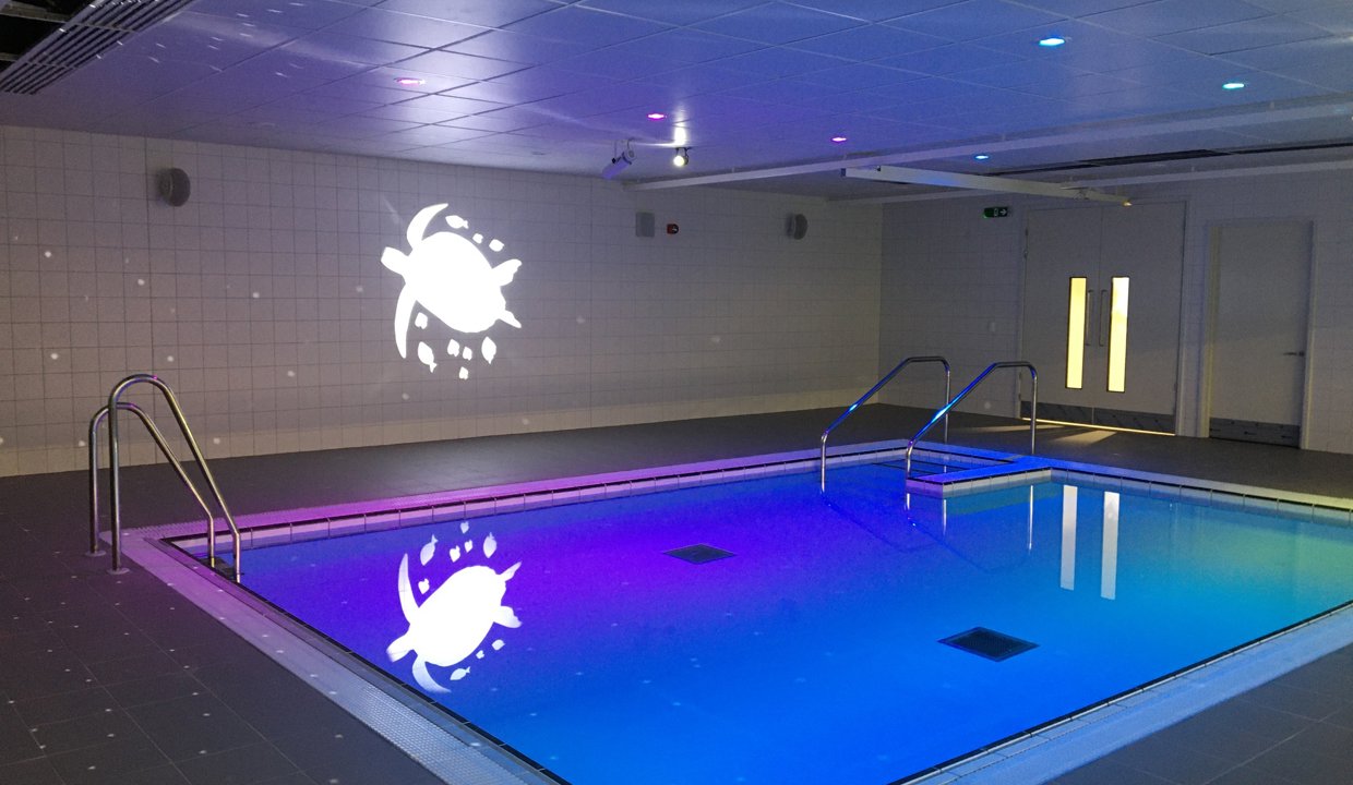The Allander hydrotherapy pool bathed in purple light, with the outline of a turtle on the wall.