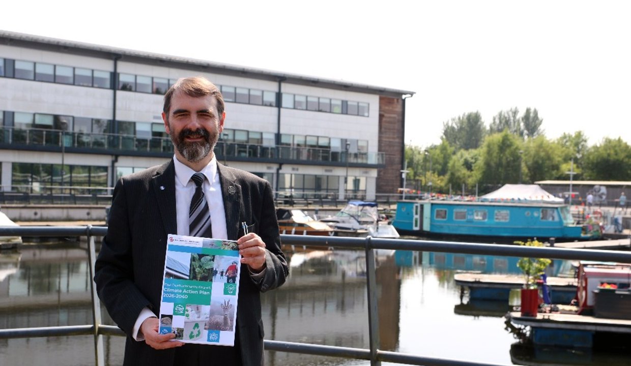 Gordan Low holding a copy of the sustainability newsletter at the Southbank Marina