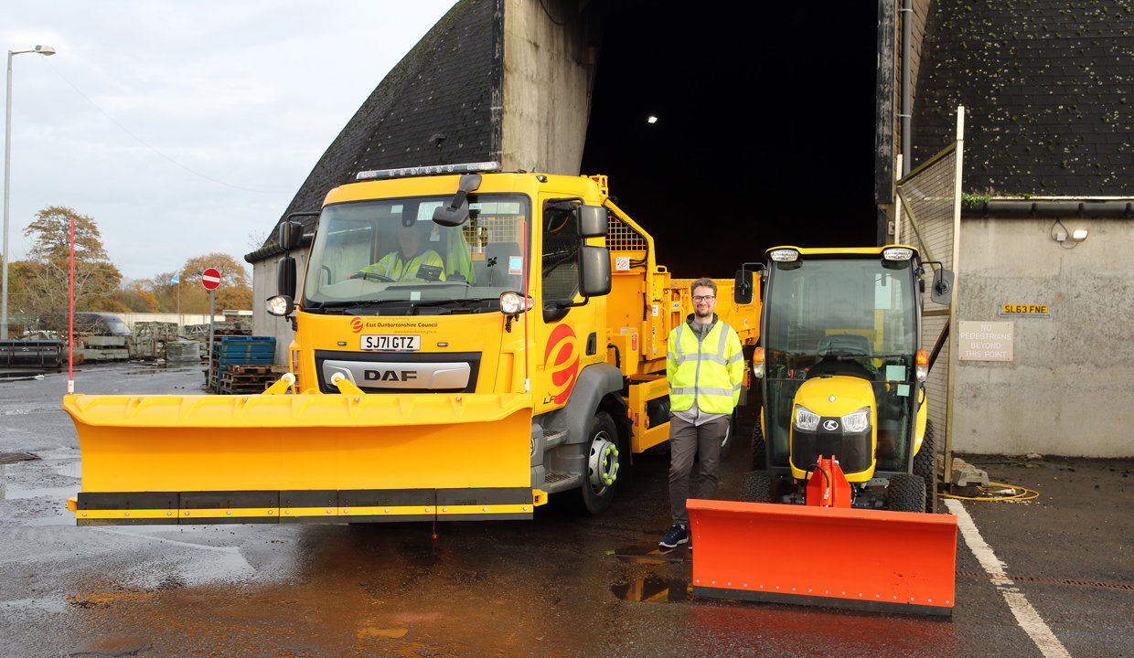 yellow gritting lorry with plow on the front and small tractor with a red plow with councillor in the middle