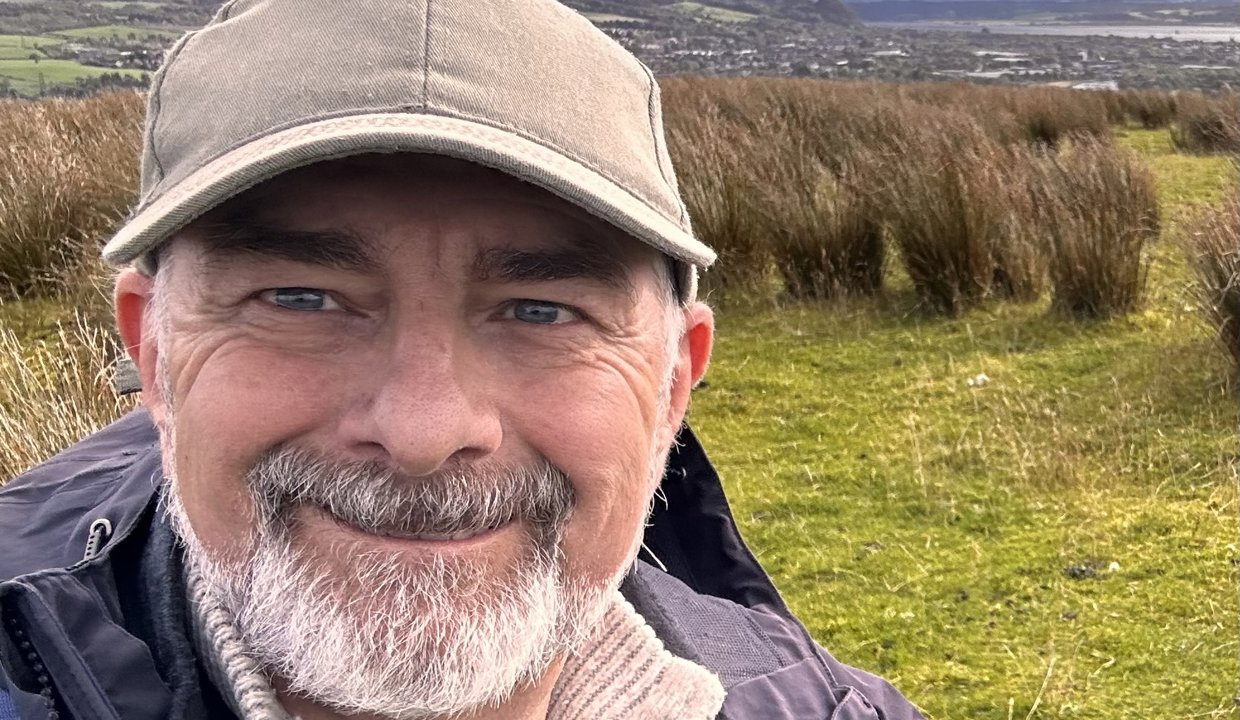 Artist Geoff Foord pictured in against a backdrop of green fields.