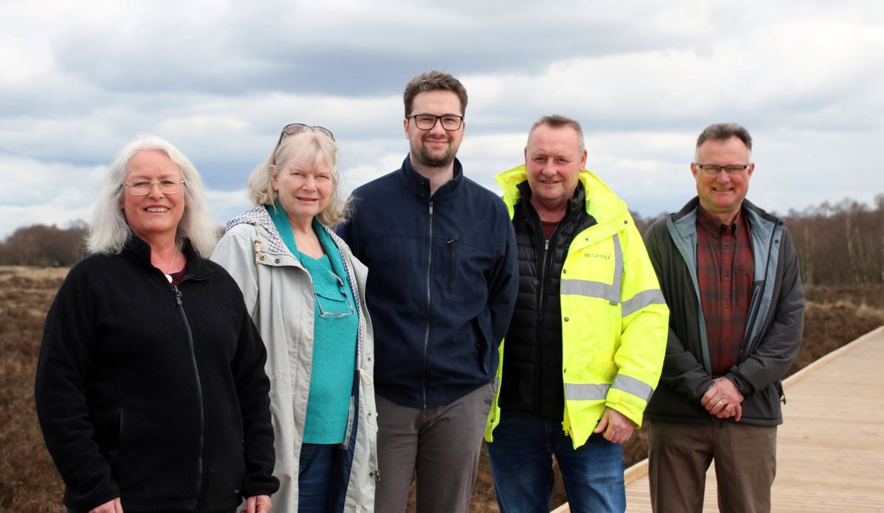 five people stand on a wooden boardwalk