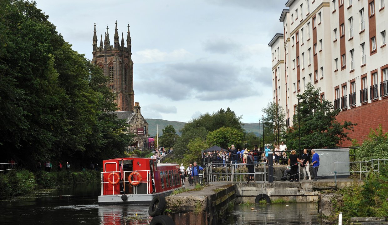A boat on the Forth and Clyde Canal with St Mary’s Church in the background