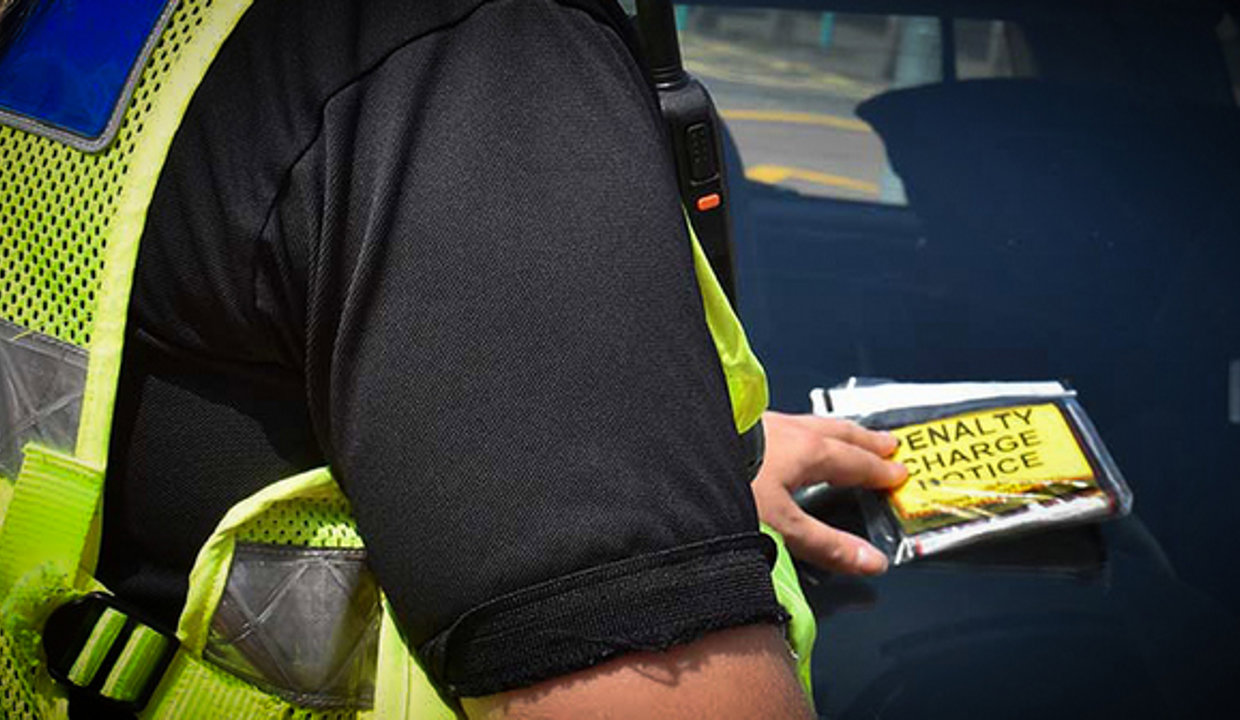 Enforcement officer placing ticket on windscreen