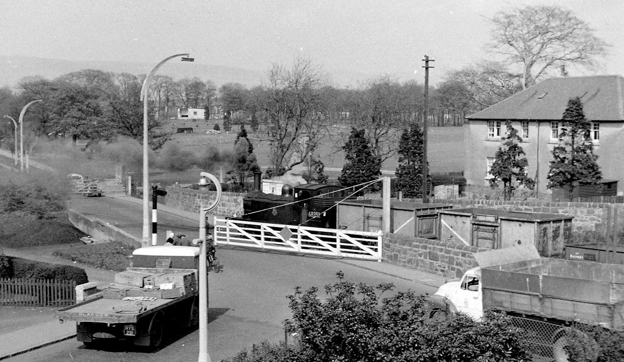 Road traffic waits at Whitegates Level Crossing while a steam locomotive crosses, 28 April 1960