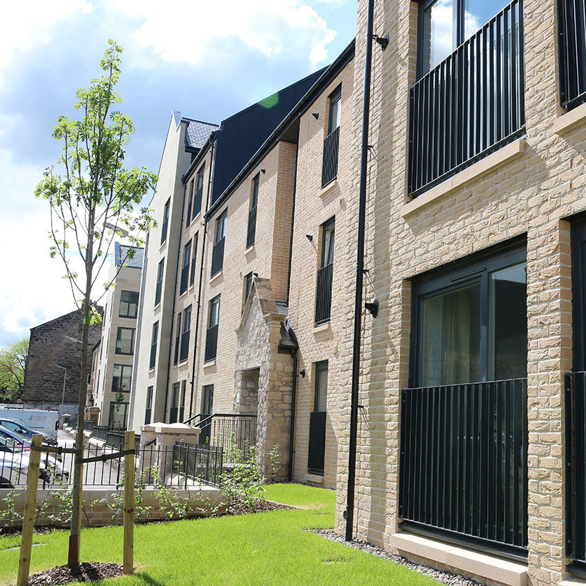 Block of housing with a small tree in the front garden