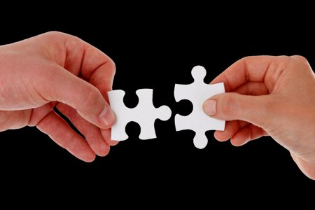 Two hands holding jigsaw puzzle pieces 