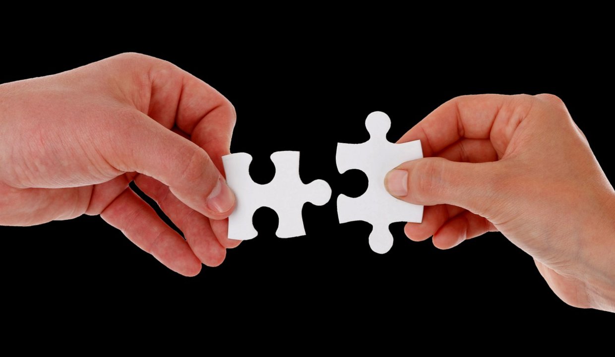 Two hands holding jigsaw puzzle pieces