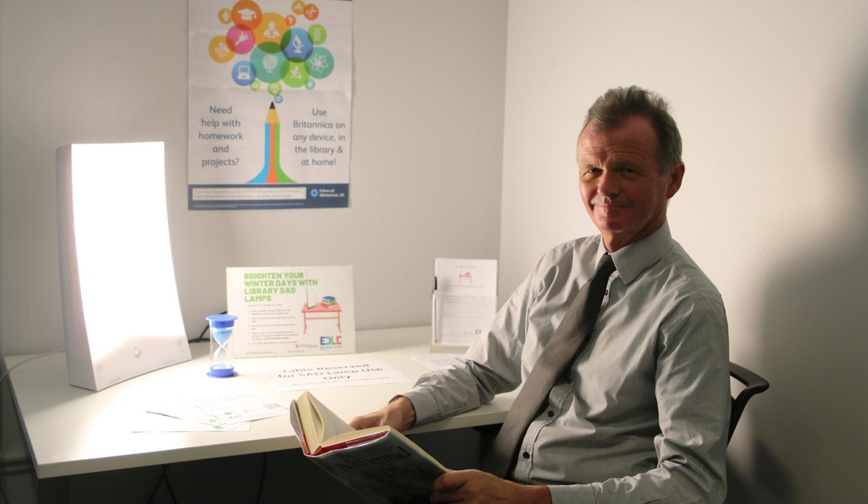 Jim Gibbons sitting in front of sad lamp