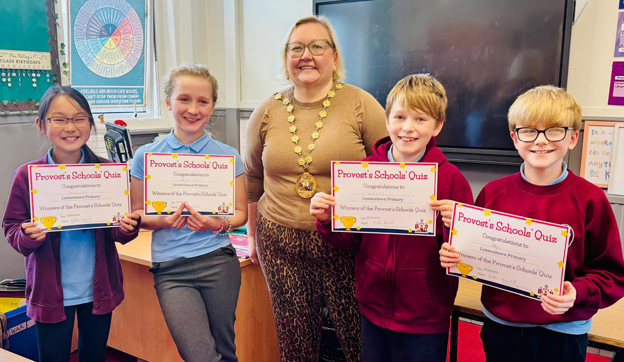 Senior pupils from Lennoxtown Primary holding up certificates and Provost renwick in a classroom 