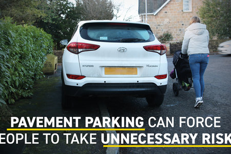 A woman pushing a pram goes onto the road around a car parked on the pavement