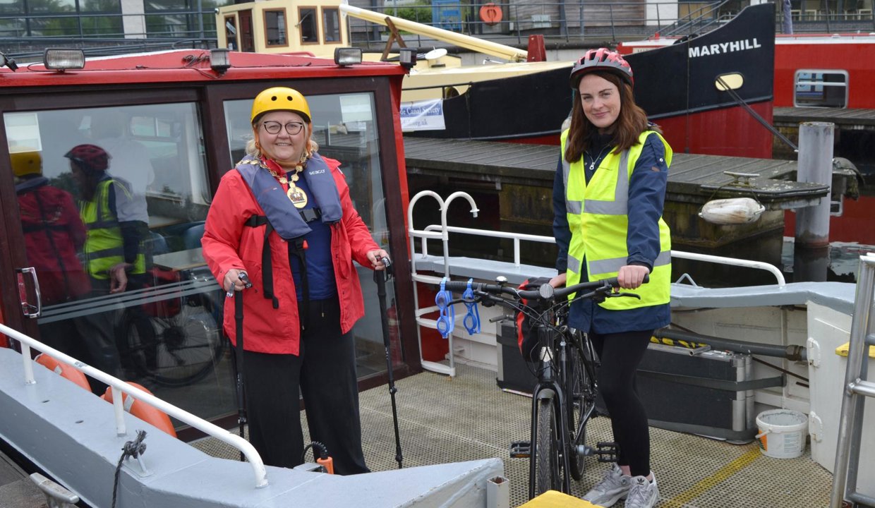Provost Gillian Renwick and Depute Provost Collette McDiarmid on a canal boat with hiking poles and a bicycle