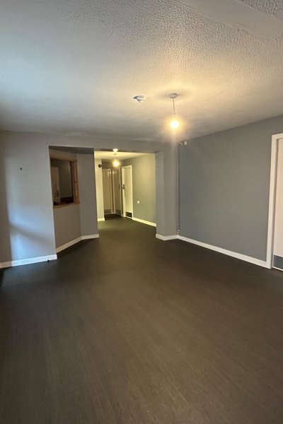main hall with a grey laminate floor and green teal pained wall and white skirting