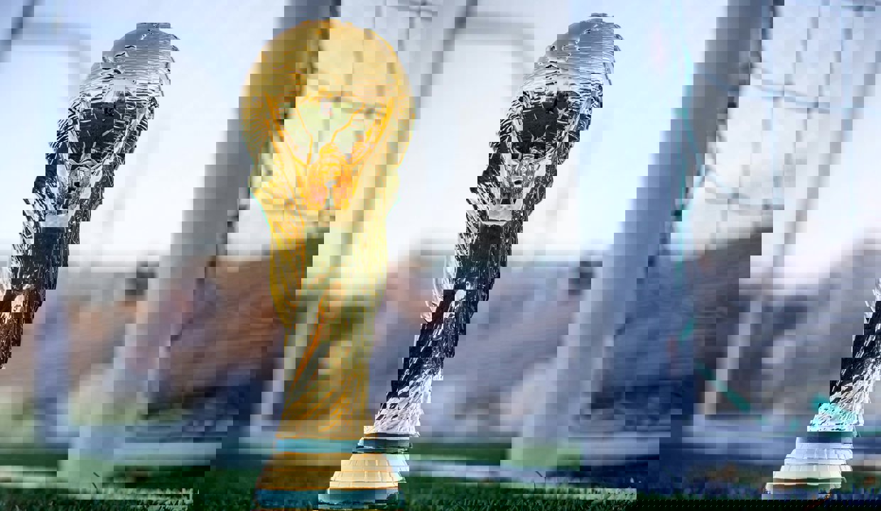 A photo of a World Cup replica trophy in front of football goals.