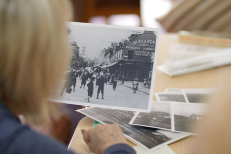 An image looking over the shoulder of a woman who is looking through archive photographs depicting local landmarks
