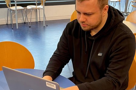 Andrew Kerr, a man who was helped to find his perfect job by EDC social work team, sits at a table working on his laptop