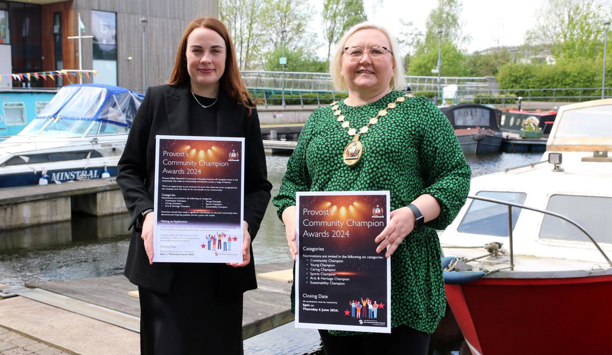 provost and deputy provost hold signs while standing in the marina