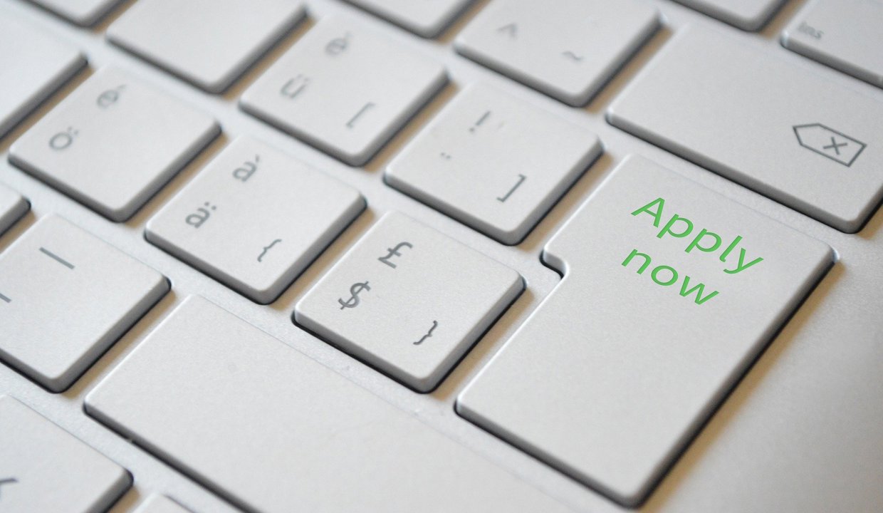 A keyboard with one of the keys featuring the words “apply now”.