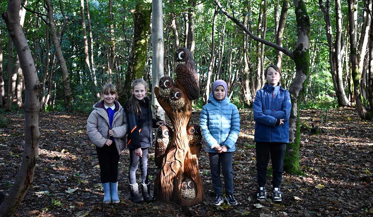 wooden sculpture of a Owls surrounded by childen and council staff