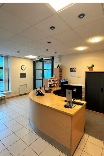 Reception area with tiled floor with a curved wooden desk and chairs