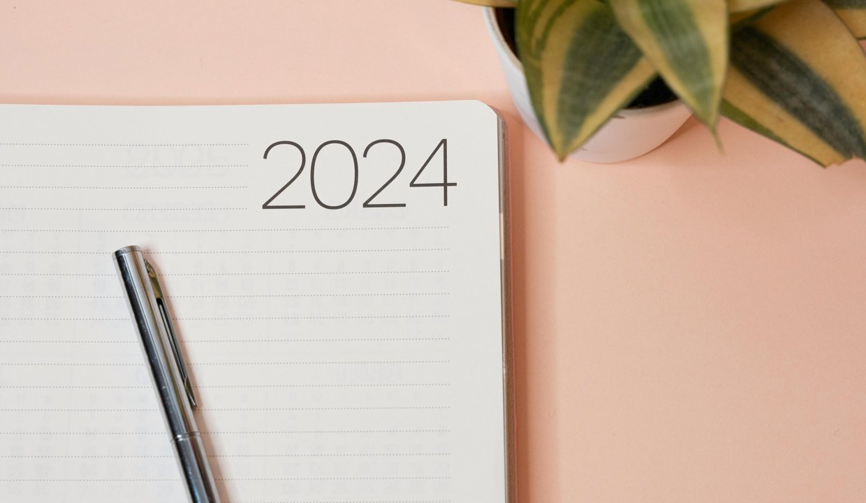 calendar with a silver pen on top with a pink background