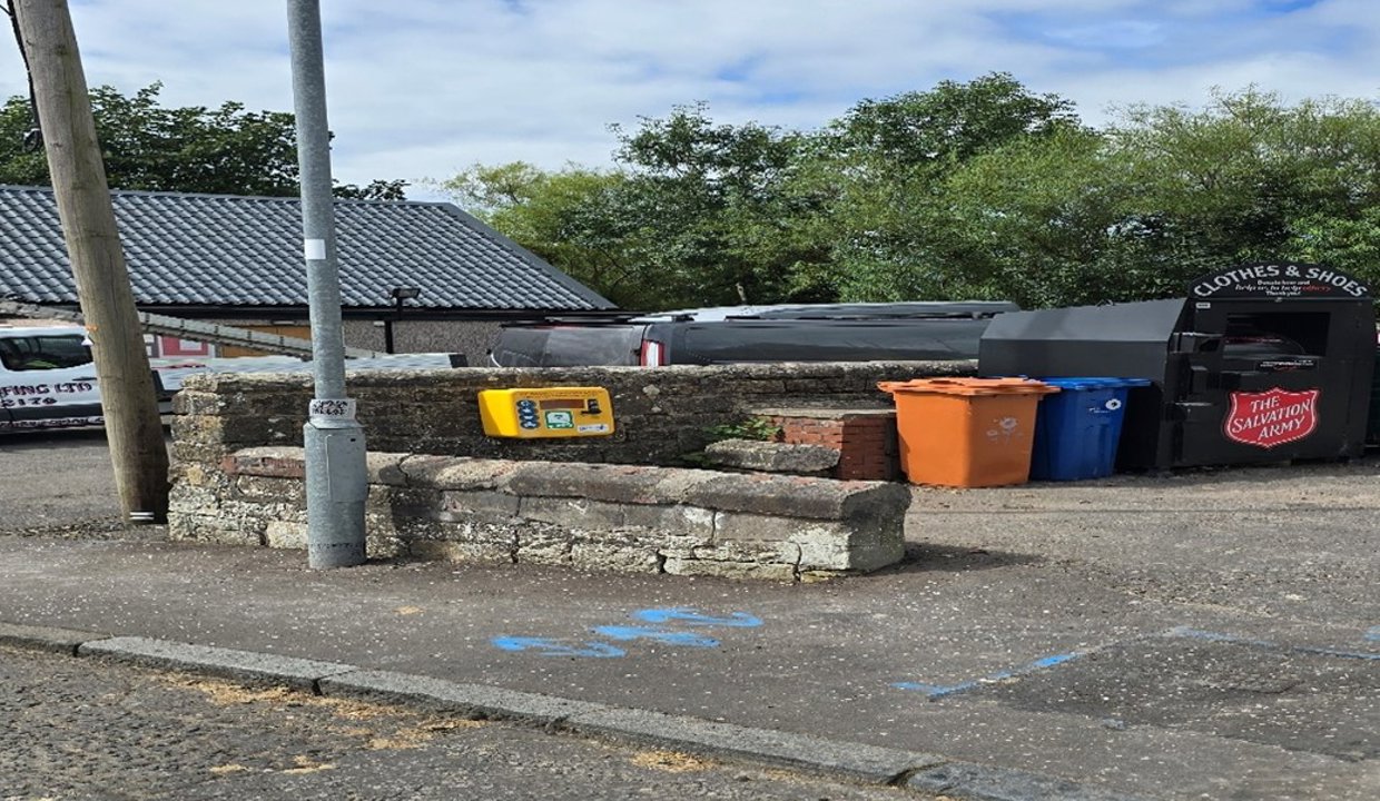 Defibrillator on wall next to bins