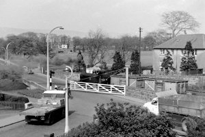 Road traffic waits at Whitegates Level Crossing while a steam locomotive crosses, 28 April 1960