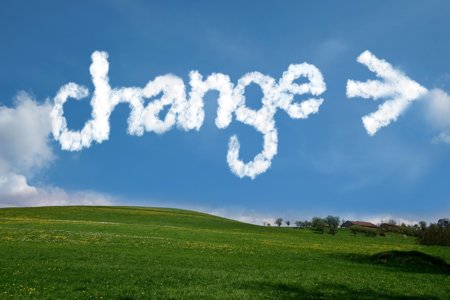clouds in the sky that form the word 'change' above a grass field