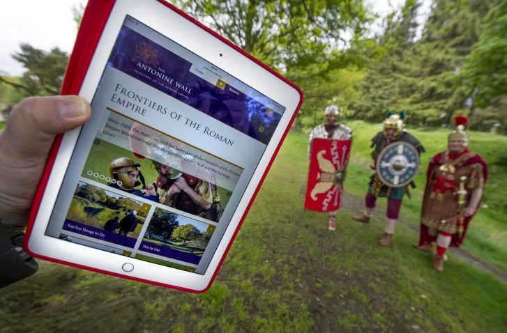 ipad showing roman empire information with 3 people dressed in roman costumes