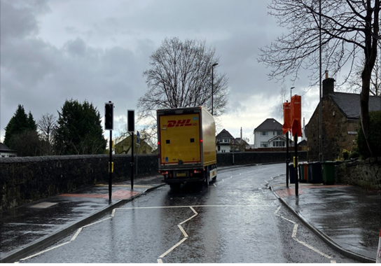 Switchback Road Crossing and Re-surfacing complete - yellow DHL lorry driving up the road through traffic lights