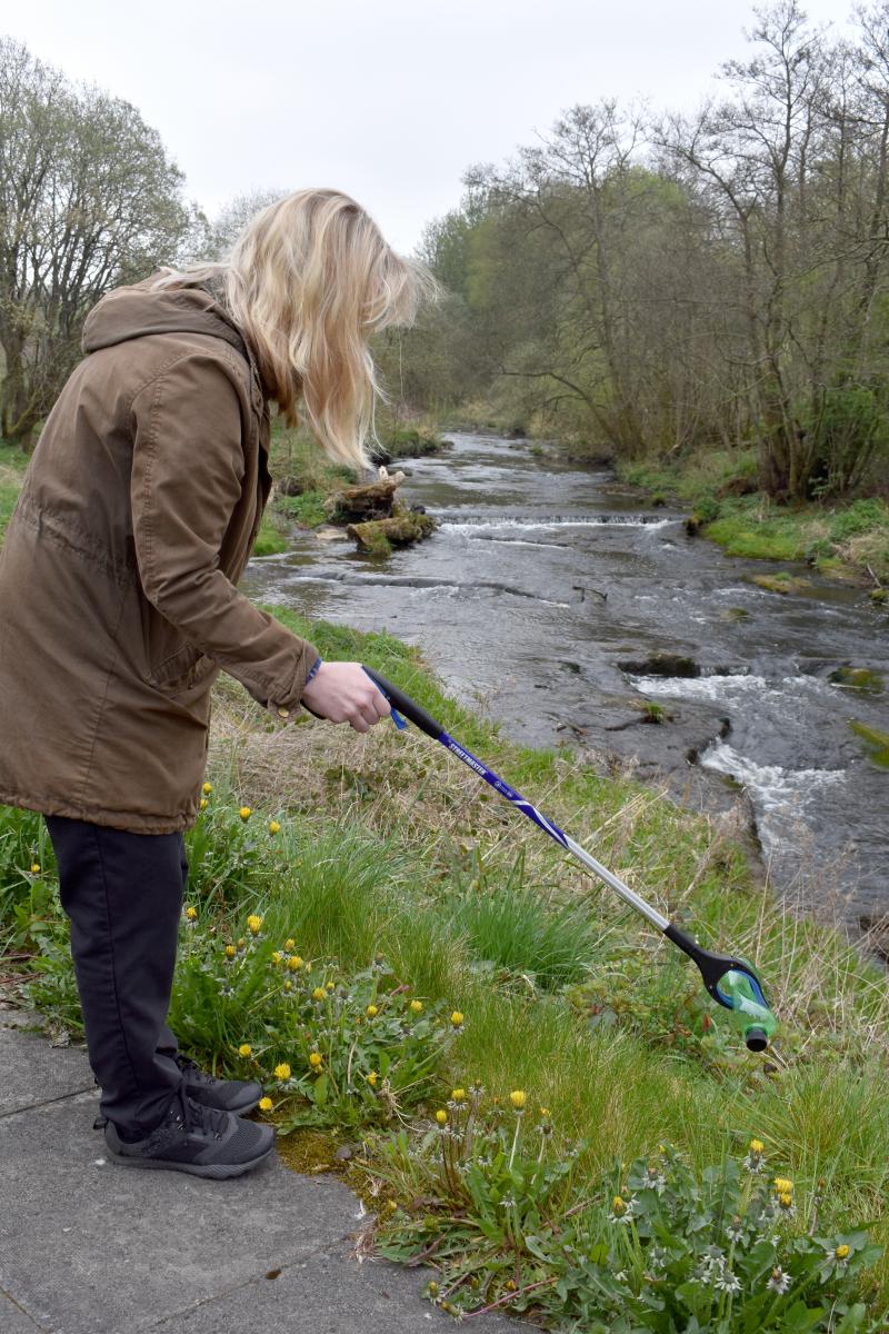image of person picking up litter from canal bank