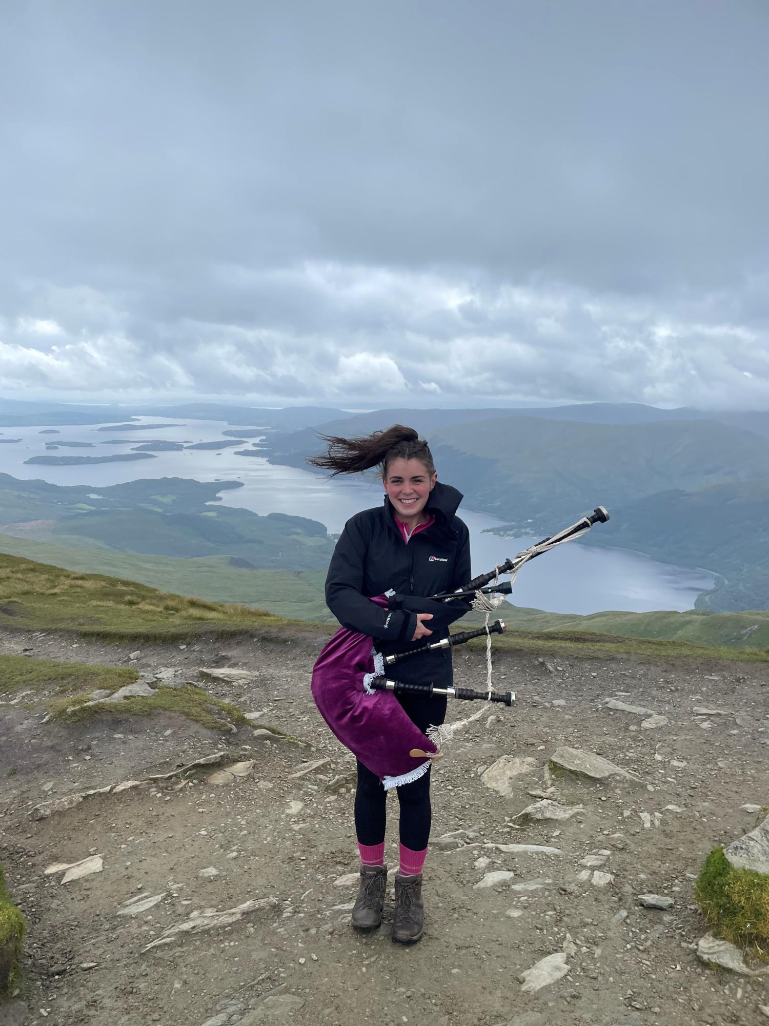 Megan holding her bagpipes at the top of Ben Lomond