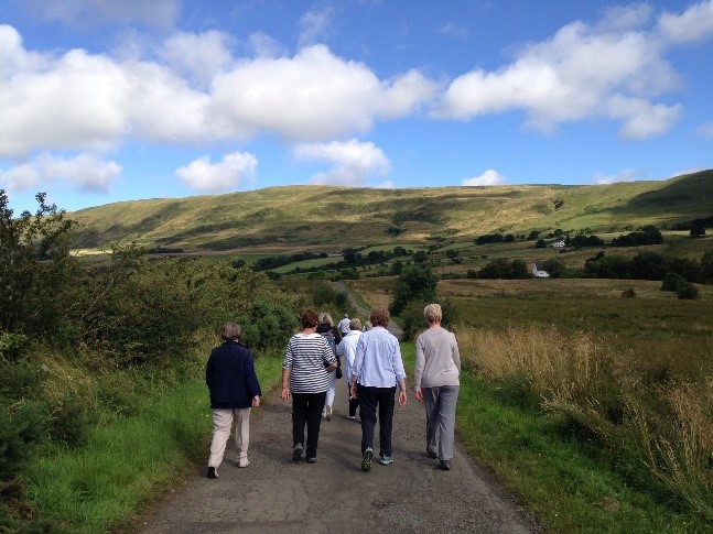 group of people walking along a path towards the campsie fells