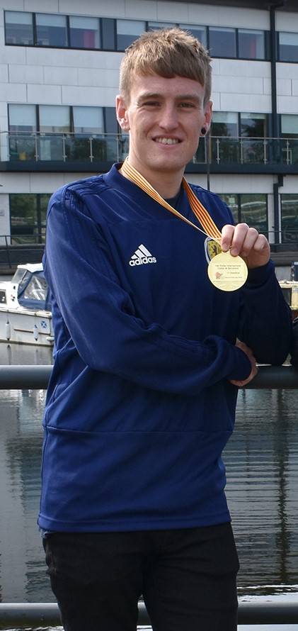 ross holding a gold medal in his scotland strip