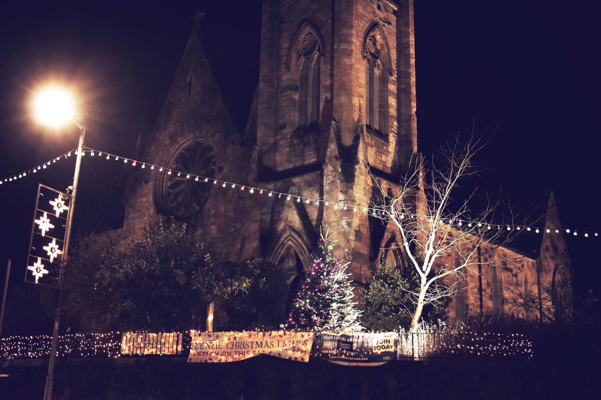 The community Christmas tree in the church grounds surrounded by fairy lights and street decorations