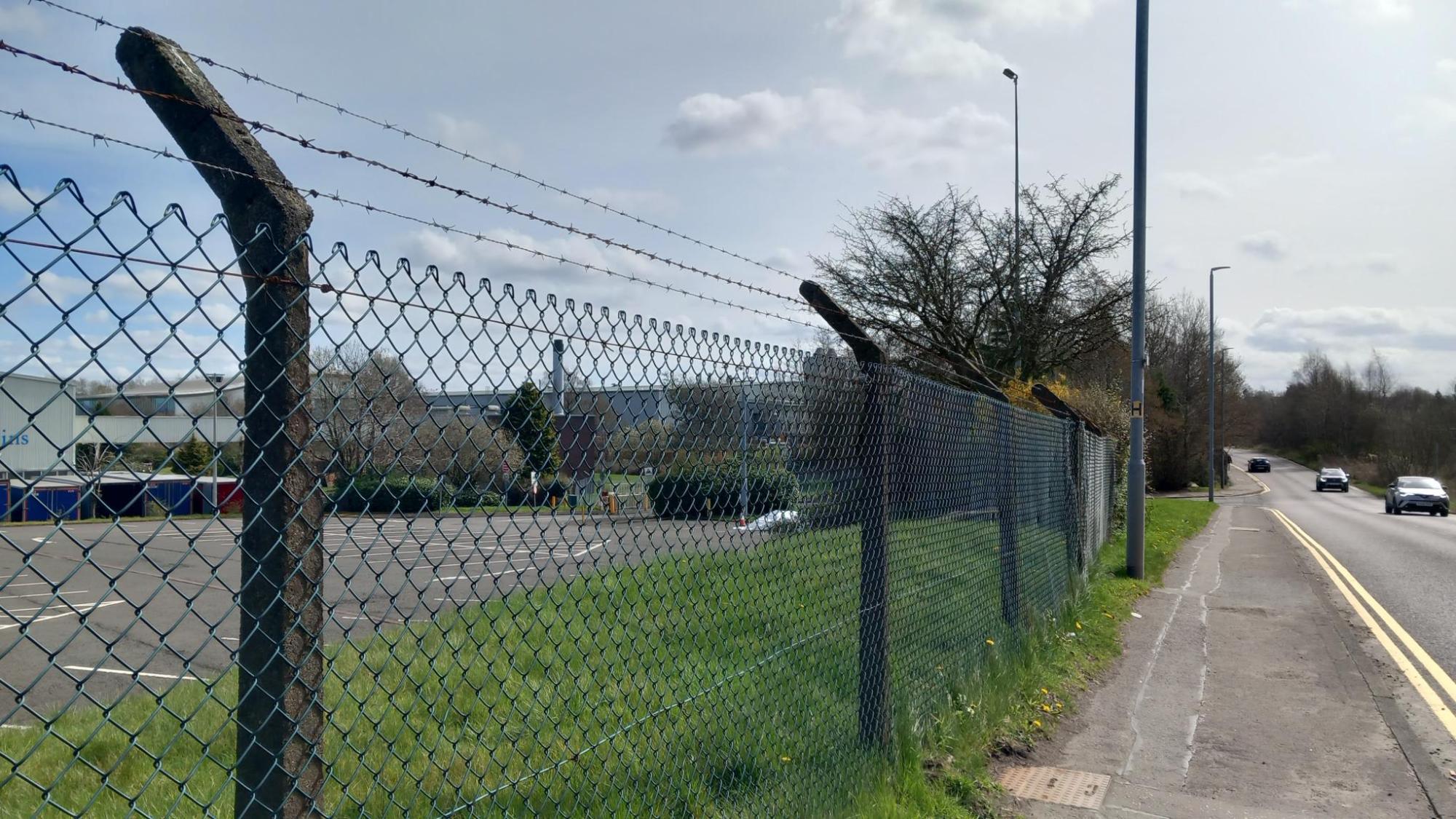 Westerhill - a fence with barbed wire and industrial units beyond